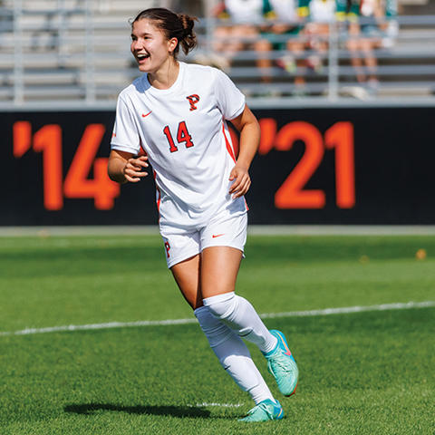 A woman in a soccer uniform, #14, runs across a field.