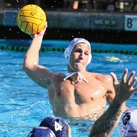 Roko Pozaric ’25 palms the ball as he prepares to throw it in a water polo game.