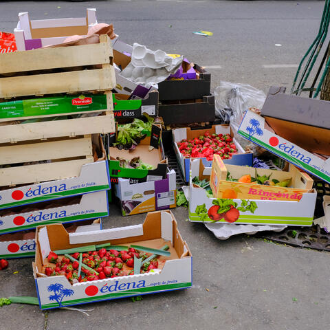 A pile of boxes of fruit line the side of a road in Paris. 