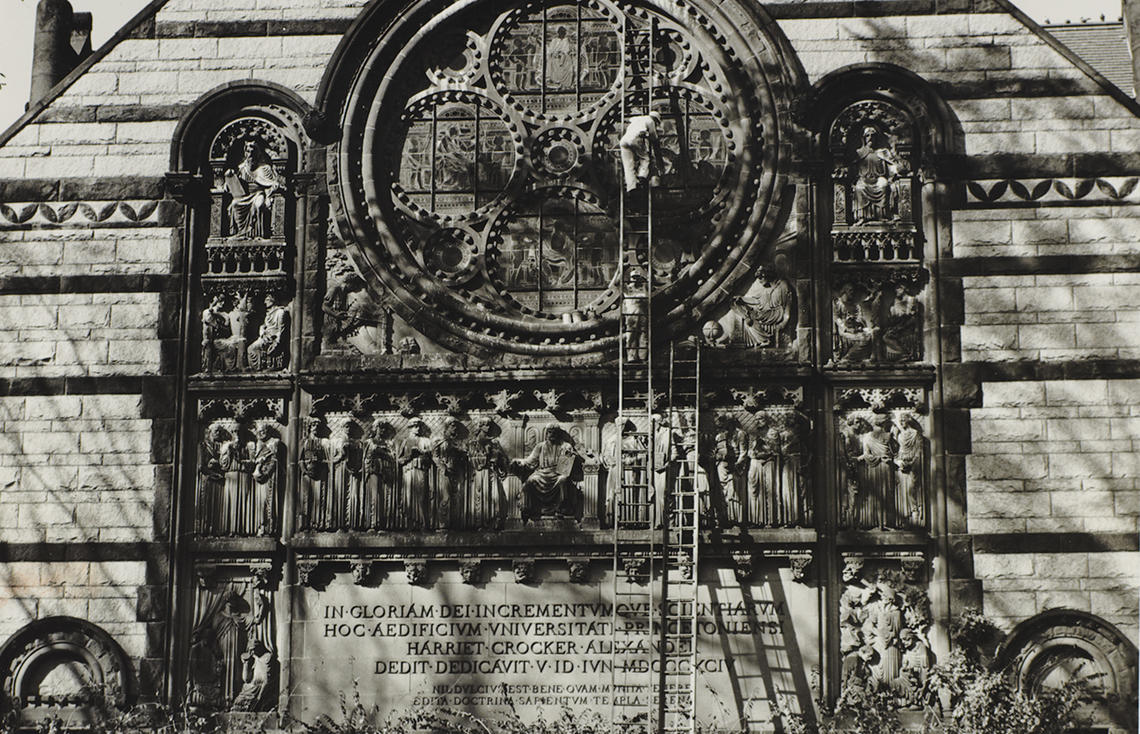 Sepia-toned photo of ladders leaning up against a stained-glass window.