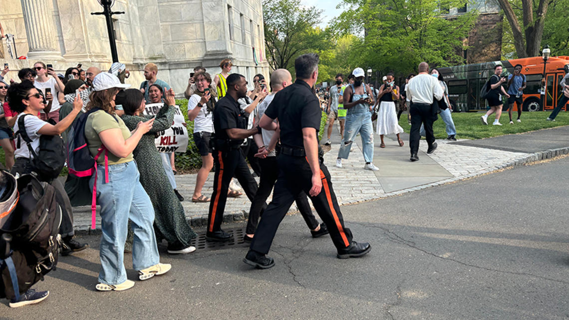 Public Safety police officers walk a man in handcuffs the night in April when student protestors staged a sit-in at Clio.