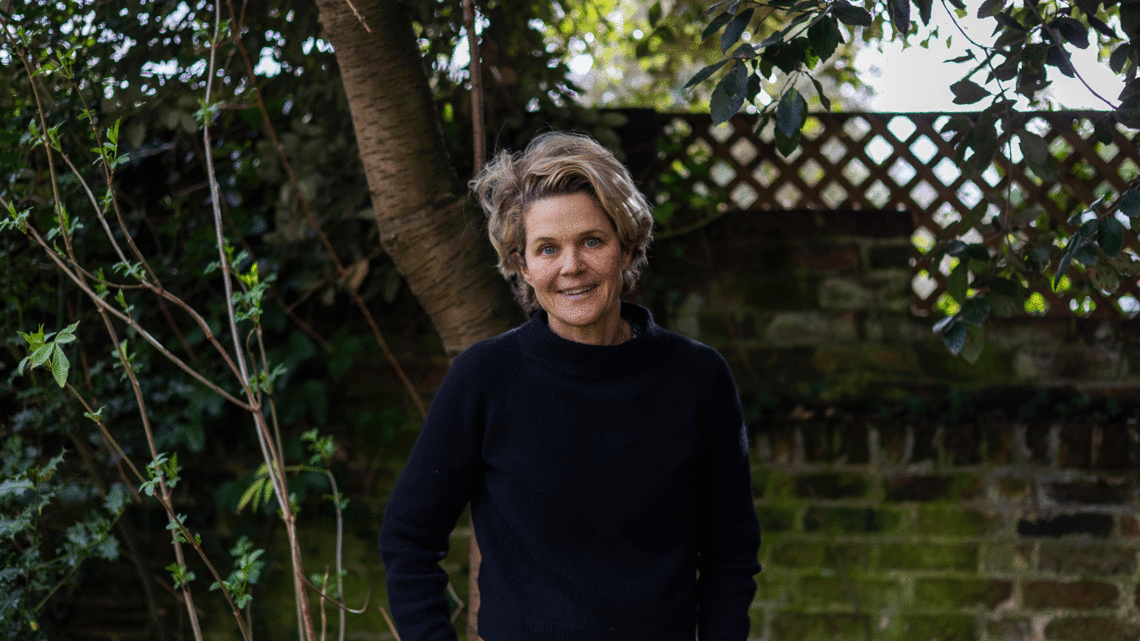 Portrait of Author Eliza Griswold standing in front of greenery. 