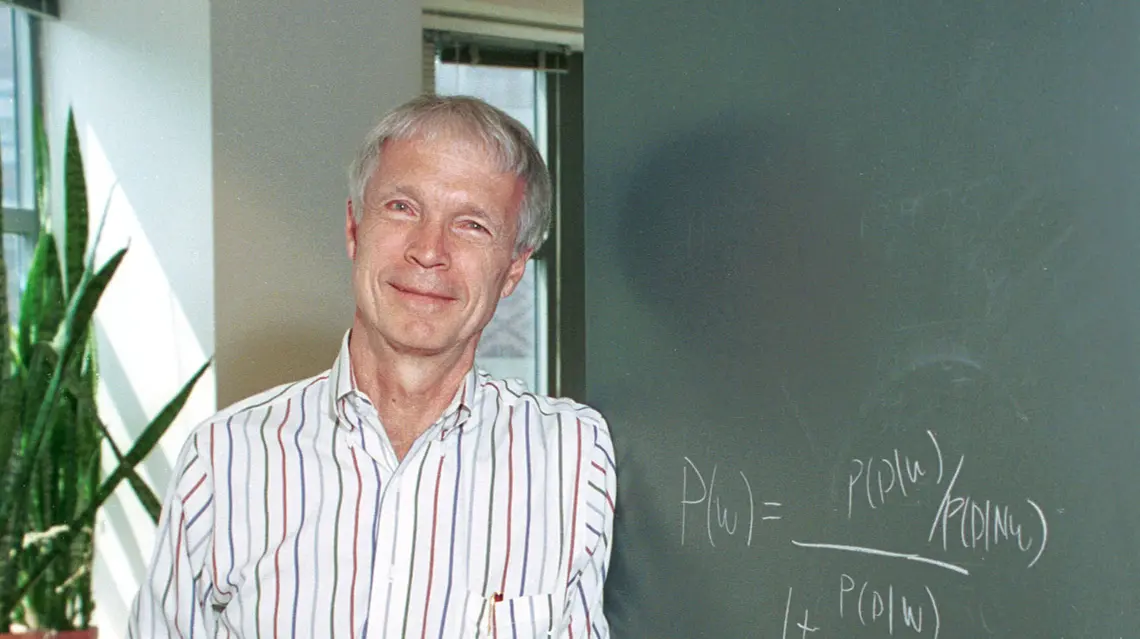 John Hopfield in front of a chalkboard