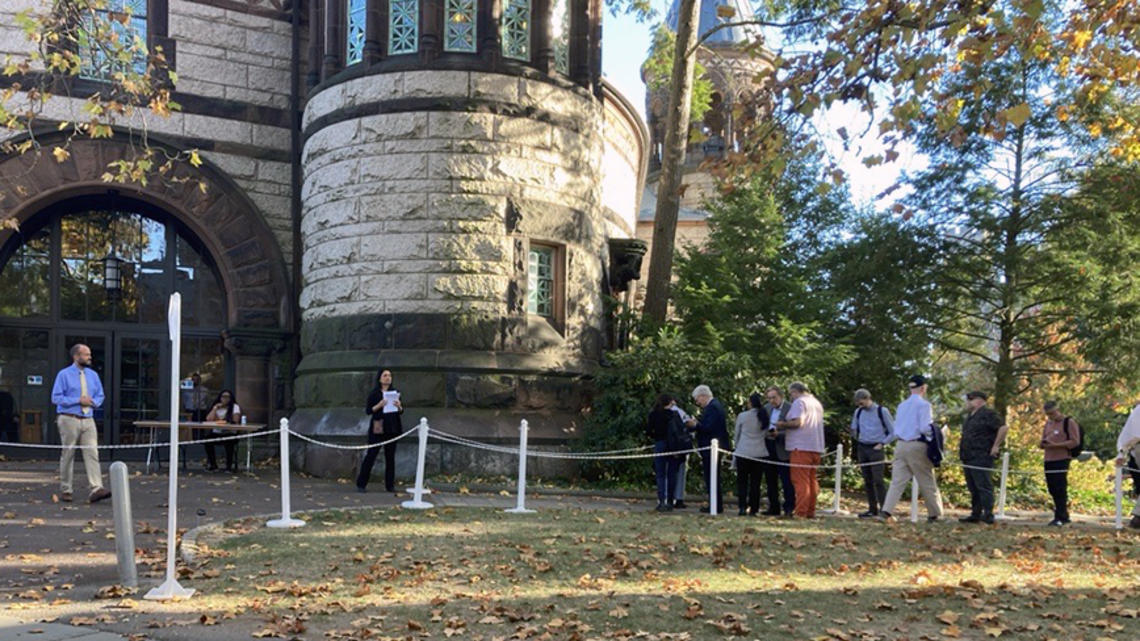 Faculty members standing in line outside a doorway