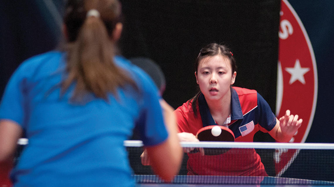 Two women play table tennis.