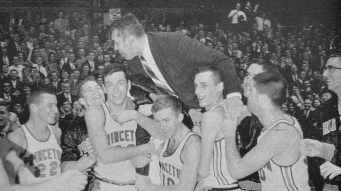 Group of basketball players lift their coach and carry him off the court