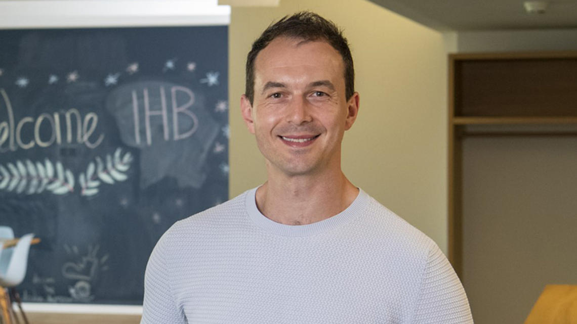 Headshot of a man with a chalkboard in the background.