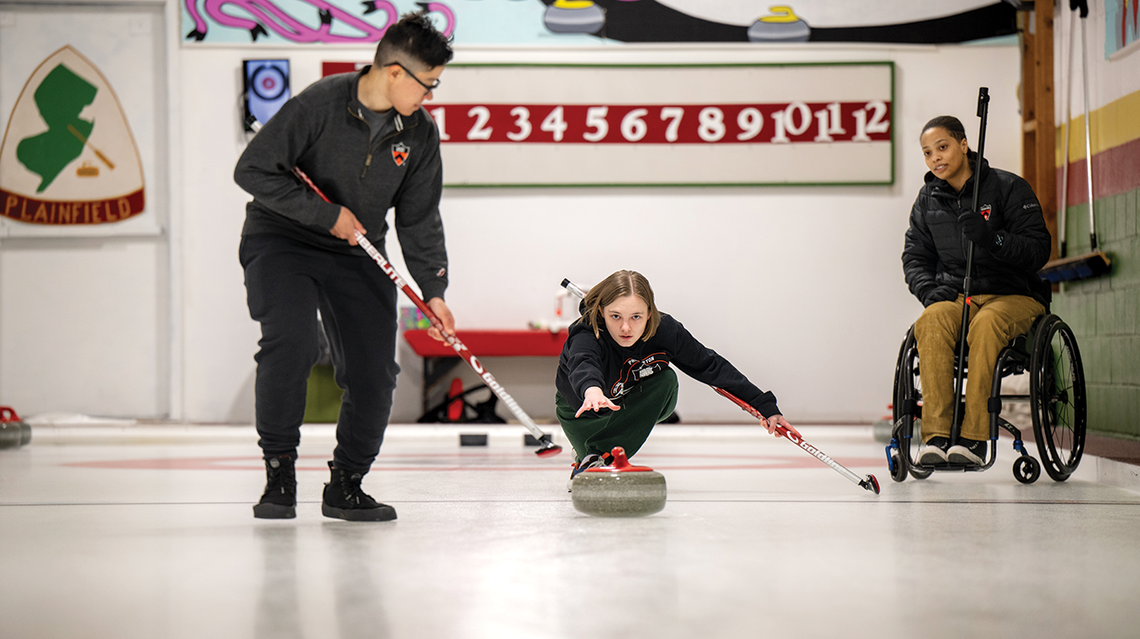 Three curling club members practice on the ice