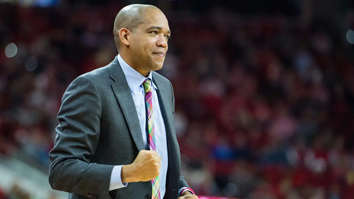 Sydney Johnson ’97 looks like something's going well as he curls one hand into a fist while coaching a basketball game.