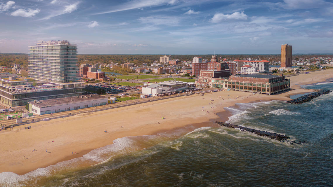 AdobeStock_658779871.jpeg An aerial photo of Asbury Park in New Jersey showing the shore line of the beach and buildings in the background.