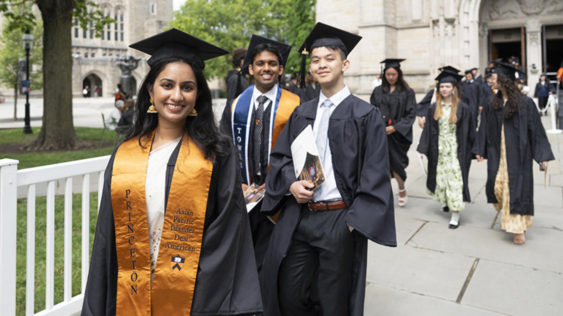 Seniors in their caps and gowns walk out of the University Chapel.