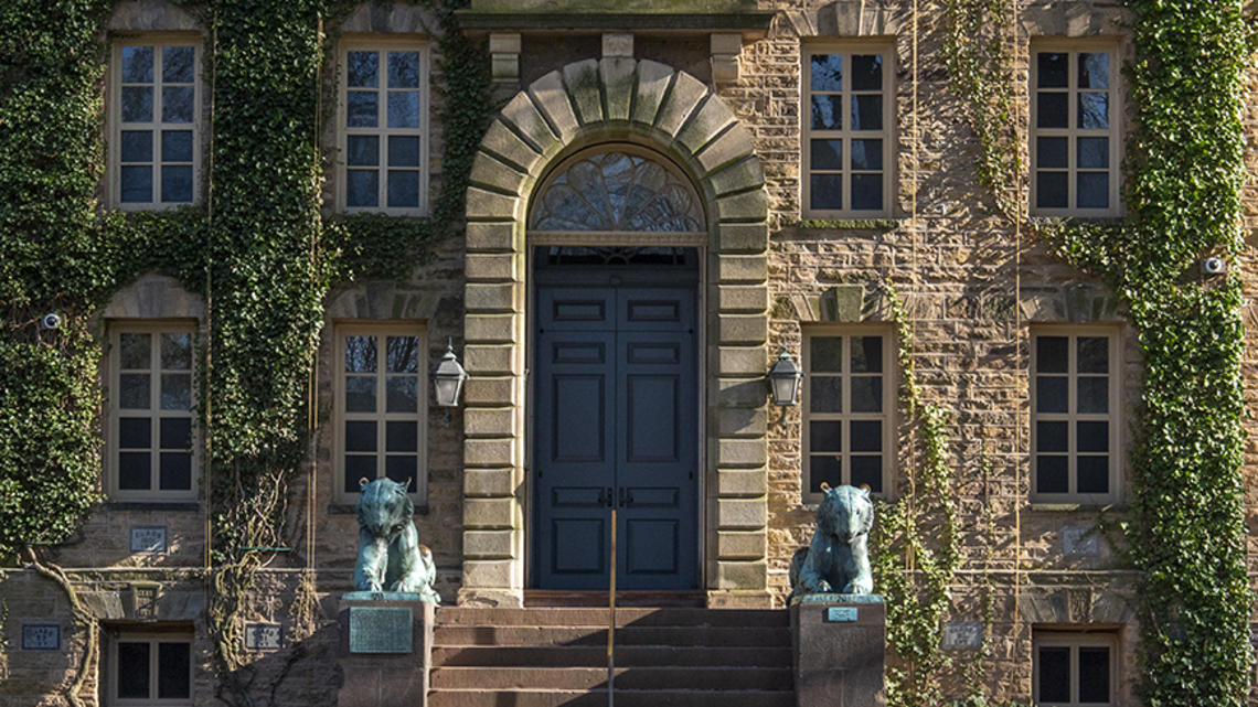 Endowment_Q&_NassauHall.jpg The front door to a stone building with paned windows, a stone archway over the door, and bronze tiger statues one each side.