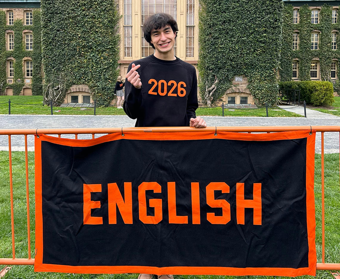 LaurenBlackburn_english_cropped.jpg Lauren Blackburn ’26 stands smiling behind a fence with a banner that reads ENGLISH in orange on a black background.