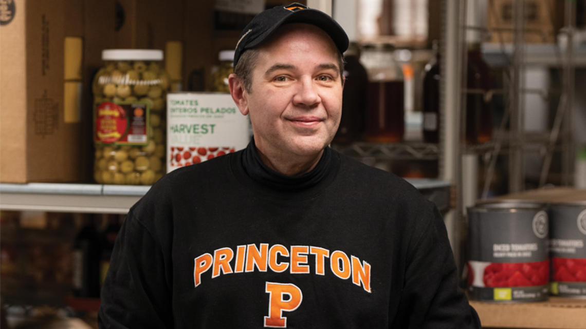 RG_Be Our Gest Damon Schunk.jpg Damon Schunk, a senior storekeeper in Campus Dining, standing in a large food pantry