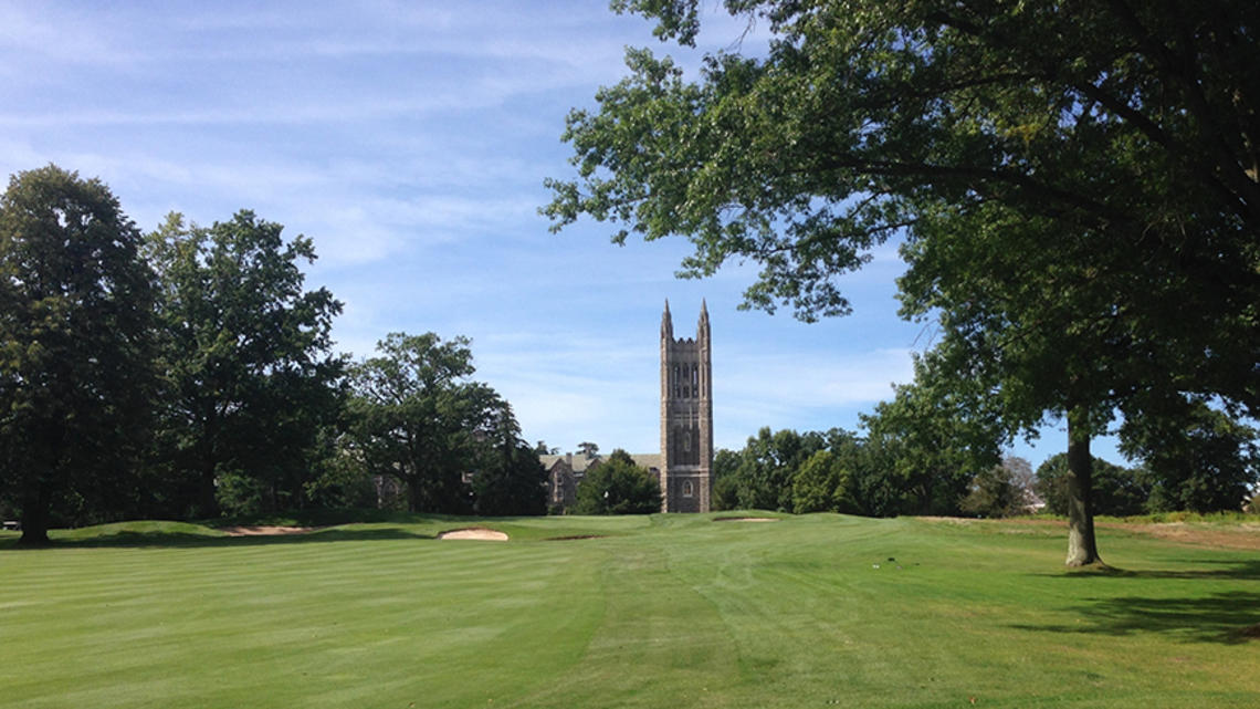 A bell tower is in the background; a golf course is in the foreground.