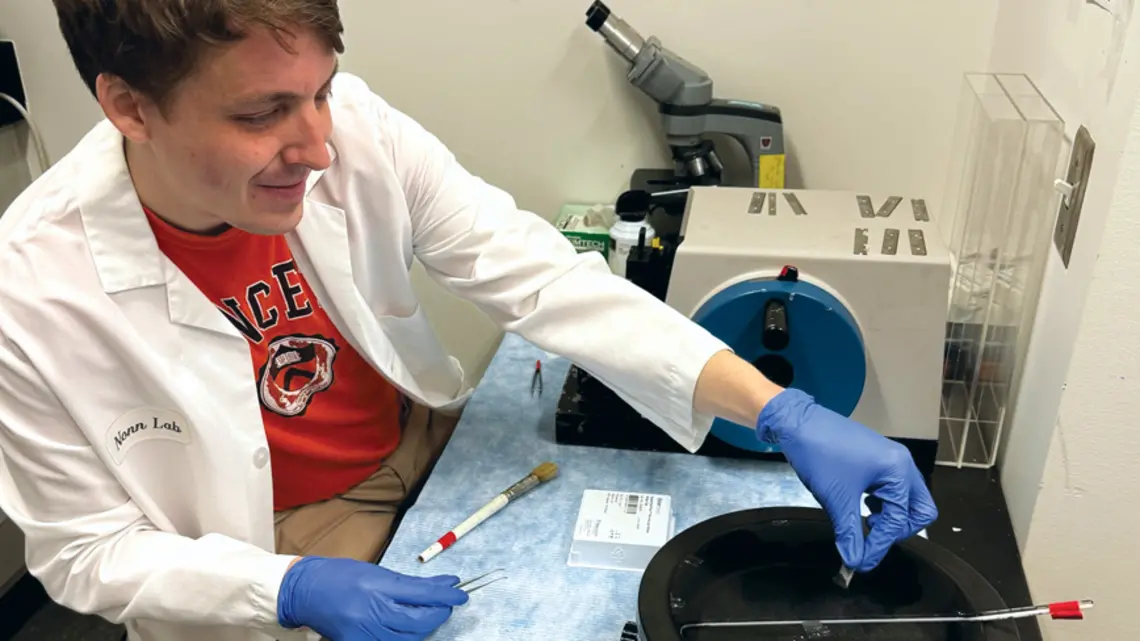 RESEARCH_Graham Read.jpg Graham Read ’15 wearing a white lab coat works in his lab
