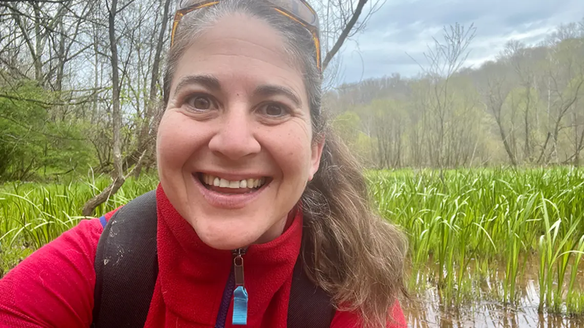Karen Showalter in front of a river full of grasses.