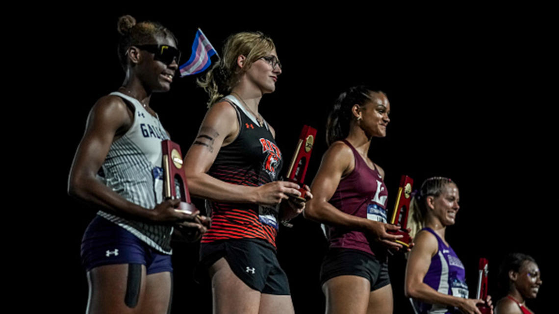 Winning athletes hold their trophies on the awards stand at the end of a track meet.