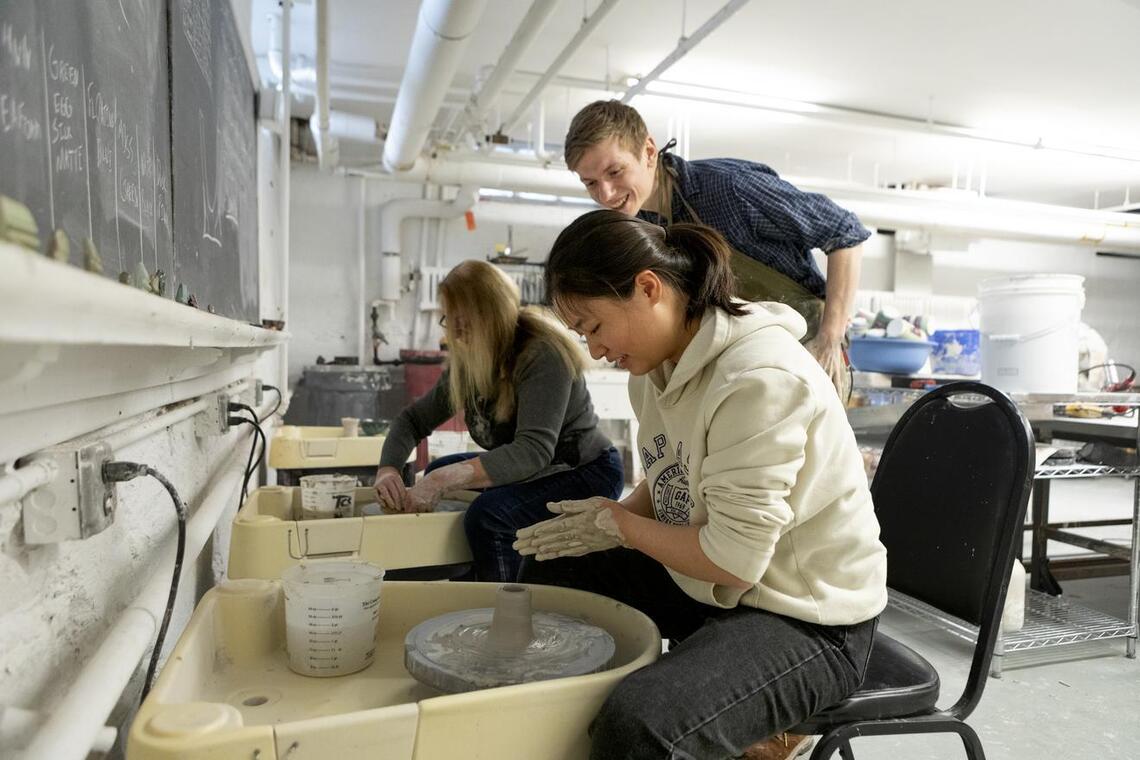 Students and instructor at pottery wheels