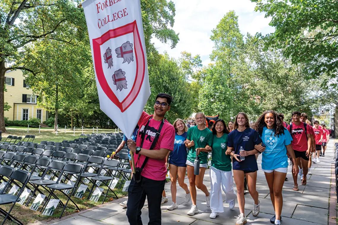 20250831_OpeningExercises_DJA_018.jpg Students marching; one at the front carries a red-and-white "Forbes College" banner.