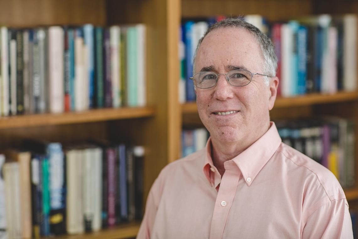 This is a shoulders-and-up photo of Gene M. Grossman with a bookcase in the background.