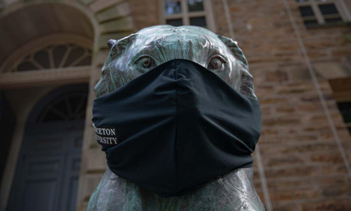 A bronze tiger statue in front of Nassau Hall wears a black face mask.