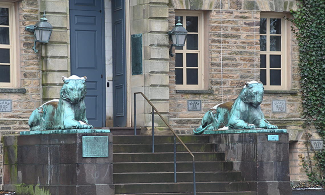 Two bronze tiger statues flank a door on a stone building, Princeton’s Nassau Hall.