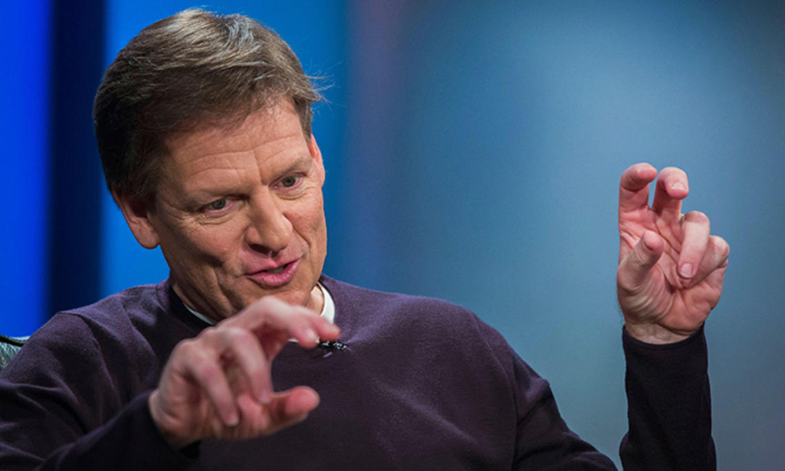 This is a photo of author Michael Lewis ’82 gesturing with his hands while he speaks during a 2014 interview at Reuters about his book “Flash Boys,” about high-frequency trading. 