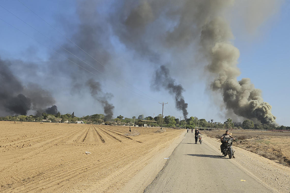 Palestinians walk away from a kibbutz, near the border fence with the Gaza Strip, while carrying out a deadly cross-border attack in southern Israel on Oct. 7, 2023.