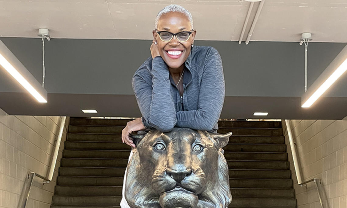 Deborah Saint Phard leans forward over a statue of a tiger.