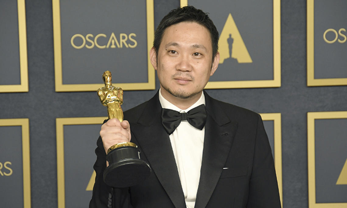 Director Ryusuke Hamaguchi holds an Oscar statue.
