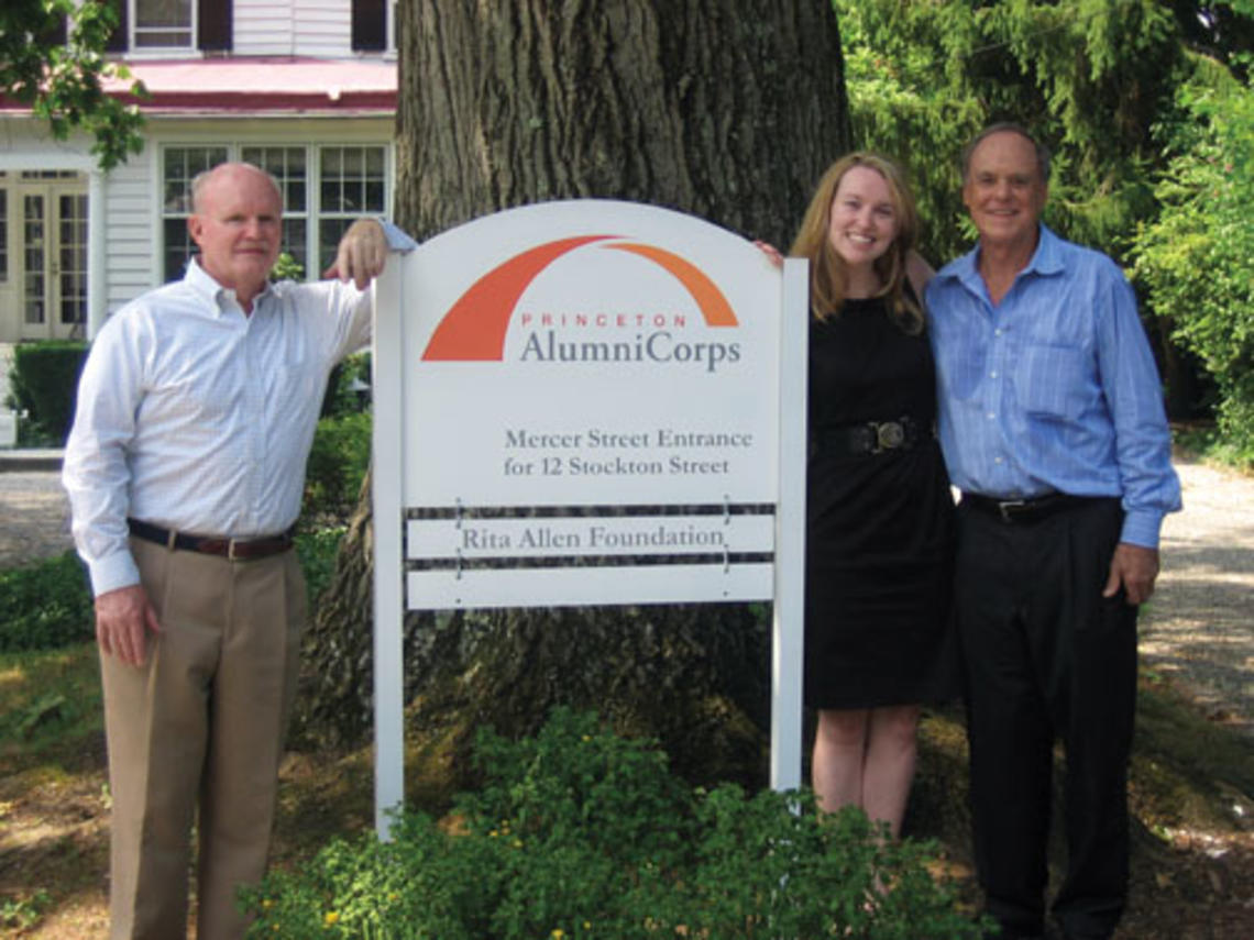  Standing next to the sign introducing Princeton AlumniCorps — formerly Princeton Project 55 — are, from left, president Bill Leahy ’66, executive director Kathleen Reilly, and board chairman Kenly Webster ’55.