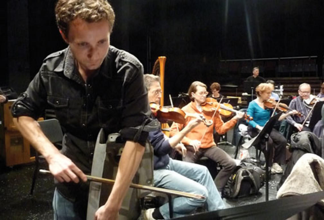 LIVE.NB_CarParts.jpg Sean Friar GS bows a car fender during a rehearsal of his “Clunker Concerto.”