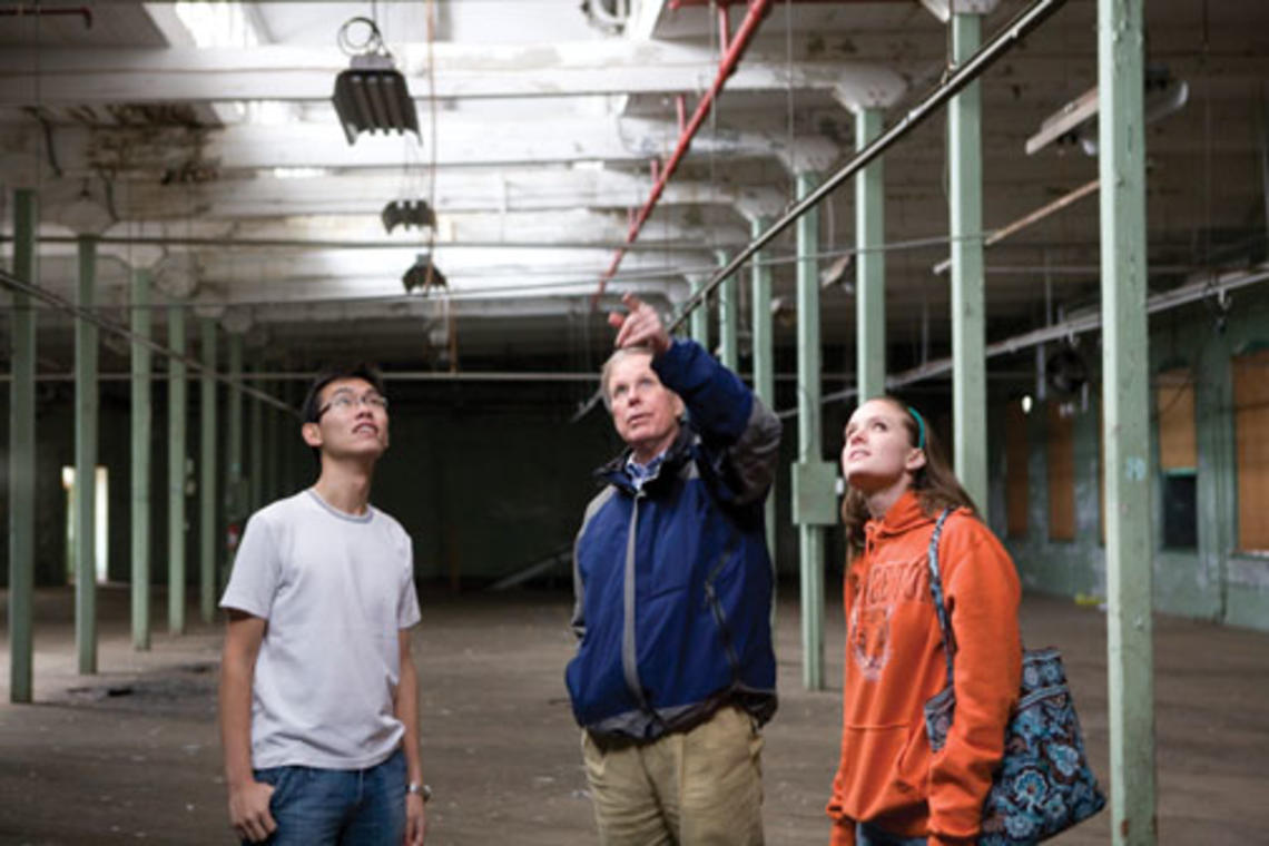 Visiting lecturer Robert Harris, center, and seniors Eric Hui and Emily Weissinger discuss the renovation of a vacant factory.