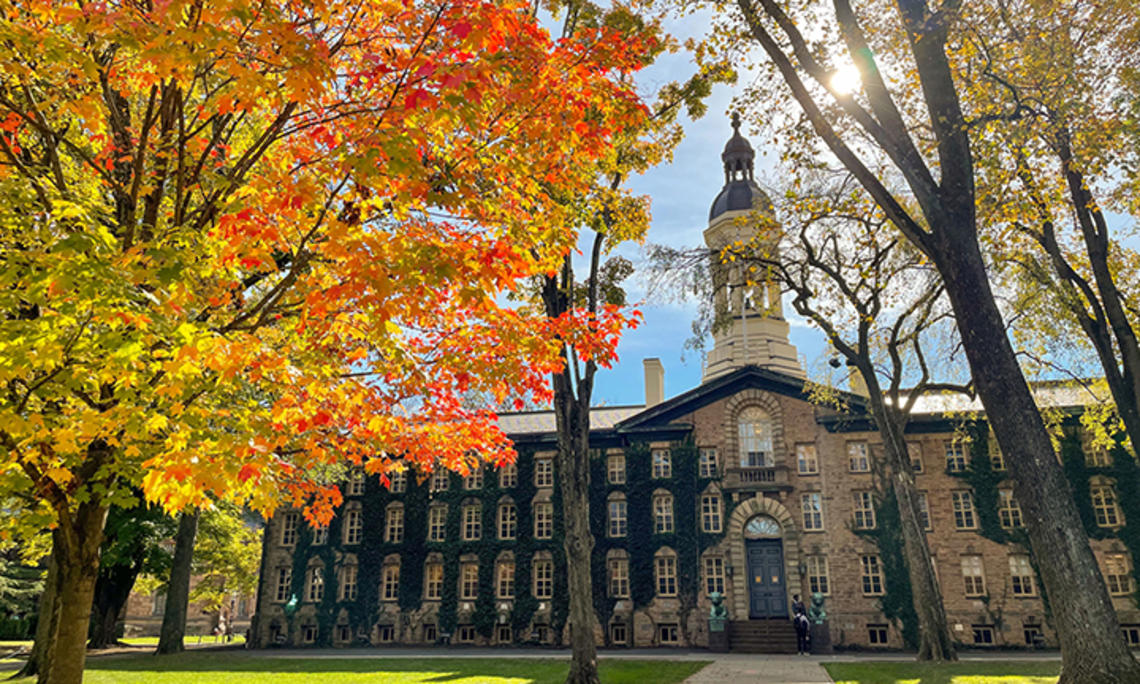 Nassau Hall in the fall, with trees turning yellow, red and orange.