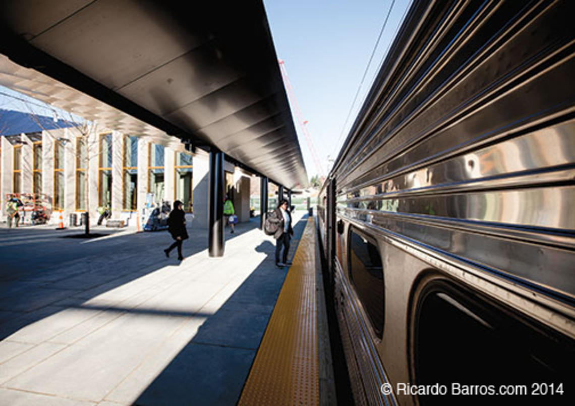 Passengers board the Dinky at the new transit plaza; the rail station is at left.