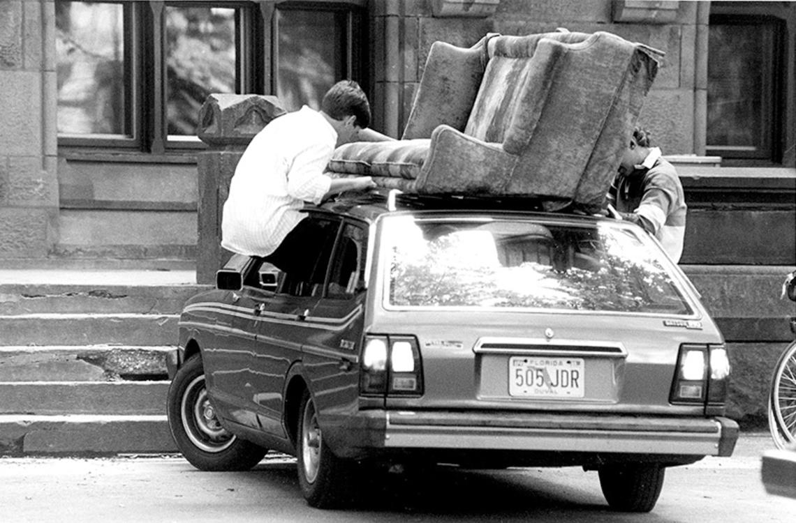 Students removing couch from the roof of a car