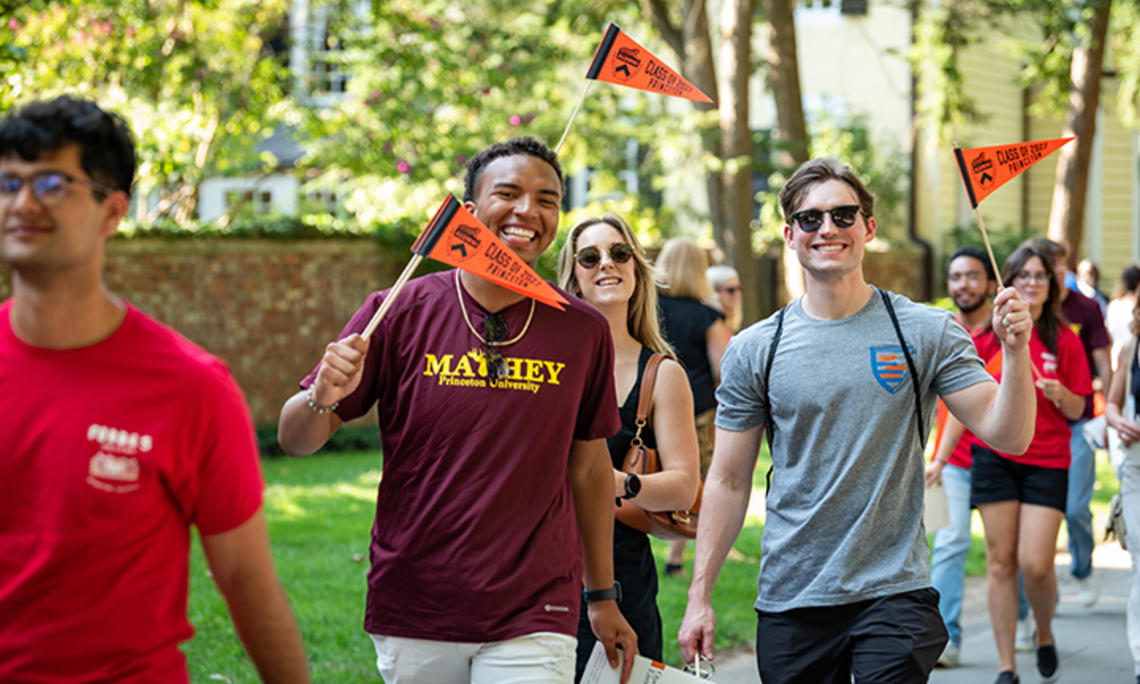 Waving orange pennants, students march in the 2023 Pre-rade.