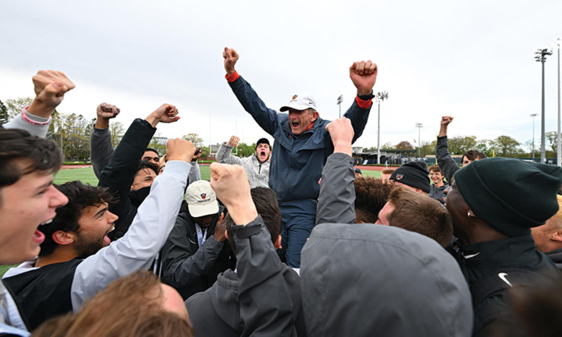 Cheering students hoist Fred Samara onto their shoulders; he holds up two fists to signal victory. 