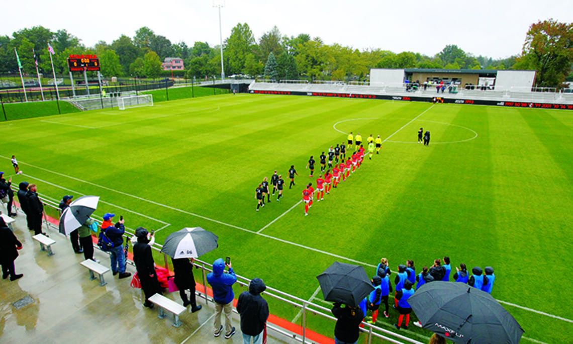 Women’s soccer players walk onto the field in two lines before the start of the game.