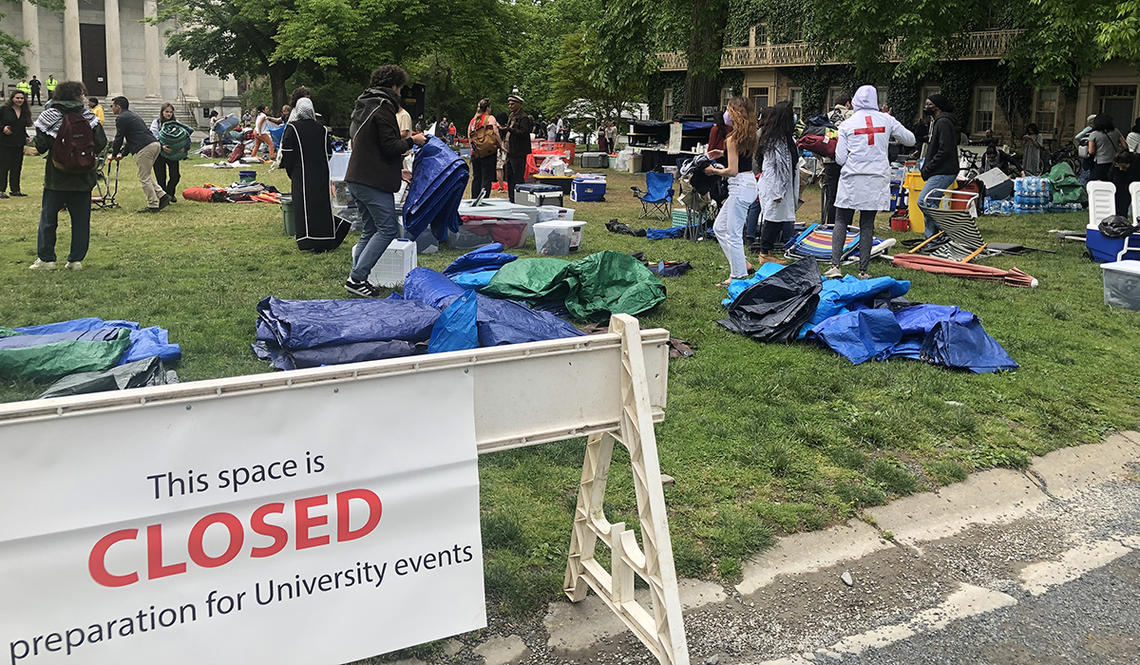 Protesters clean up Cannon Green behind a sign saying the area is now closed in preparation for University events. 