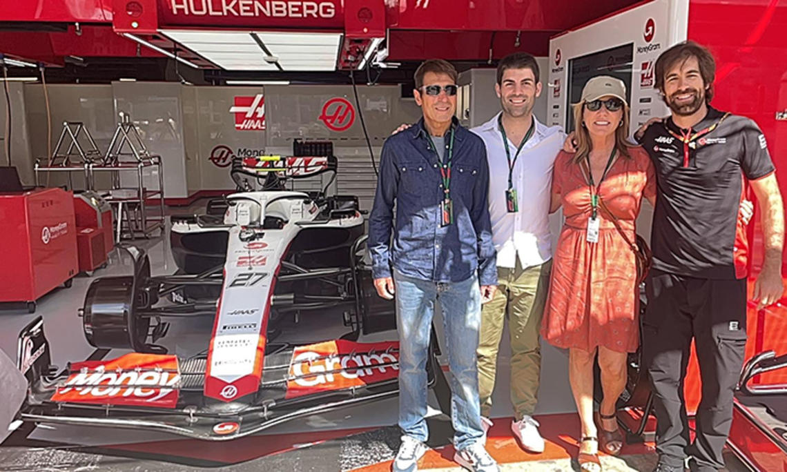 Stefano Chiazza *13 and three other people stand in a garage with a Formula 1 racecar.