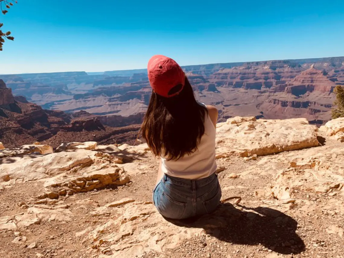 Cassandra James ’23 sits with her back to the camera, looking over a southwest scene.