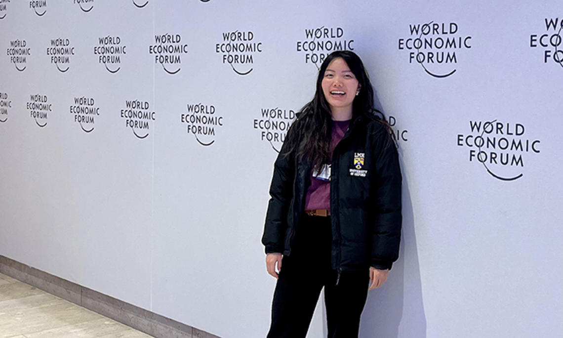 Diana Chao stands in front of a wall printed with the logo for this year's World Economic Forum.