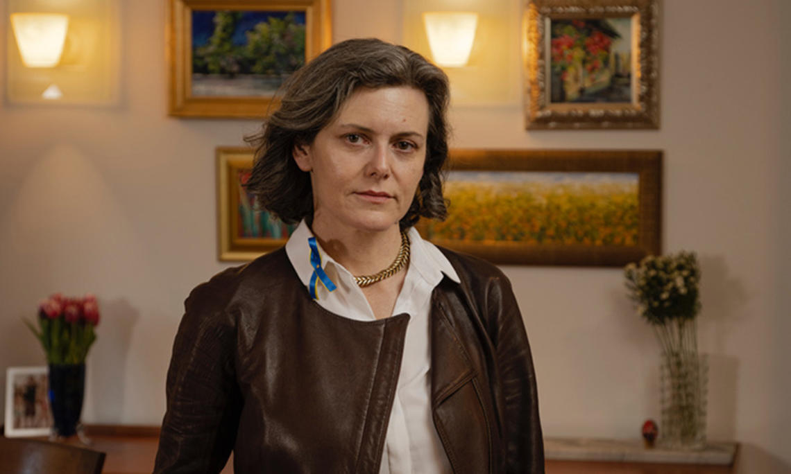 TOW_DoraChomiak.jpg This is a photo of Dora Chomiak ’91 in front of a wall hung with paintings.