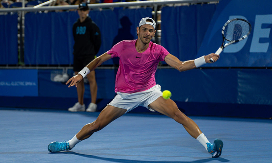 Matija Pecotić ’13 hits a tennis ball with a racket in his left hand