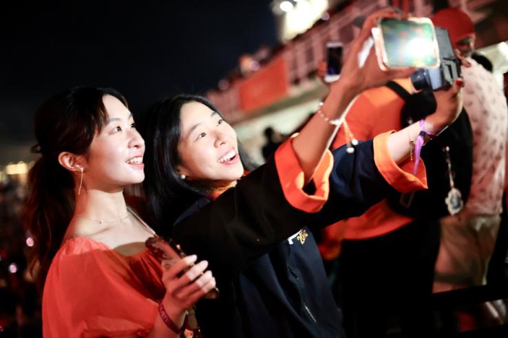 Two women take a selfie at night outdoors.