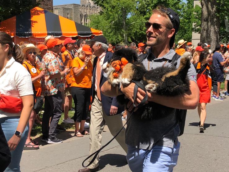 A man carries a dog in the P-rade.