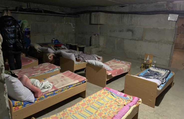 A bomb shelter below a kindergarten in central Ukraine has small beds set up with various colors of blankets.