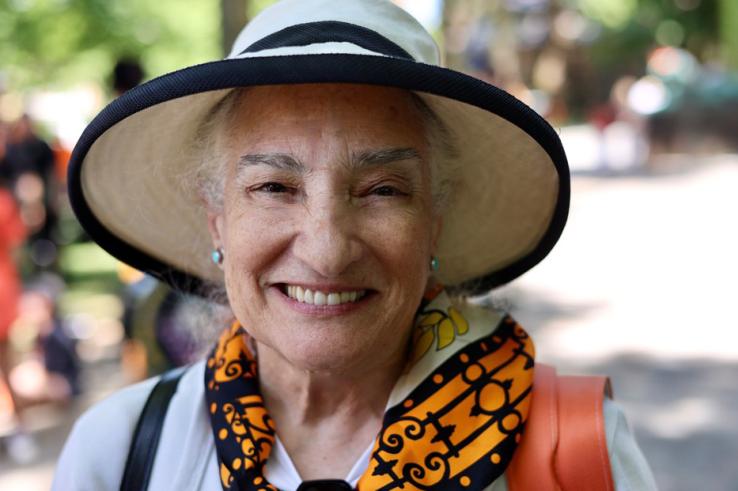 A woman in a hat and orange-and-black scarf smiles for the camera.